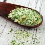 Close up image of a wooden spoon filled with basil salt.