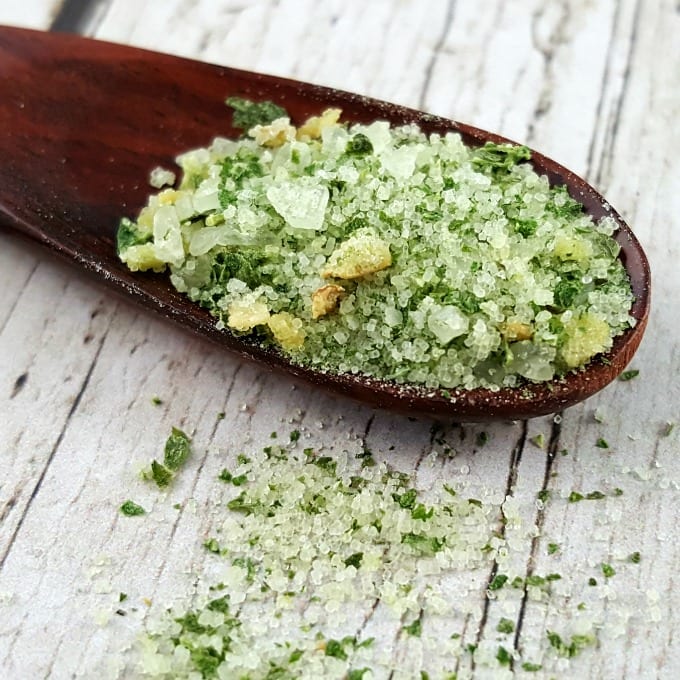 Close up image of a wooden spoon filled with basil salt.