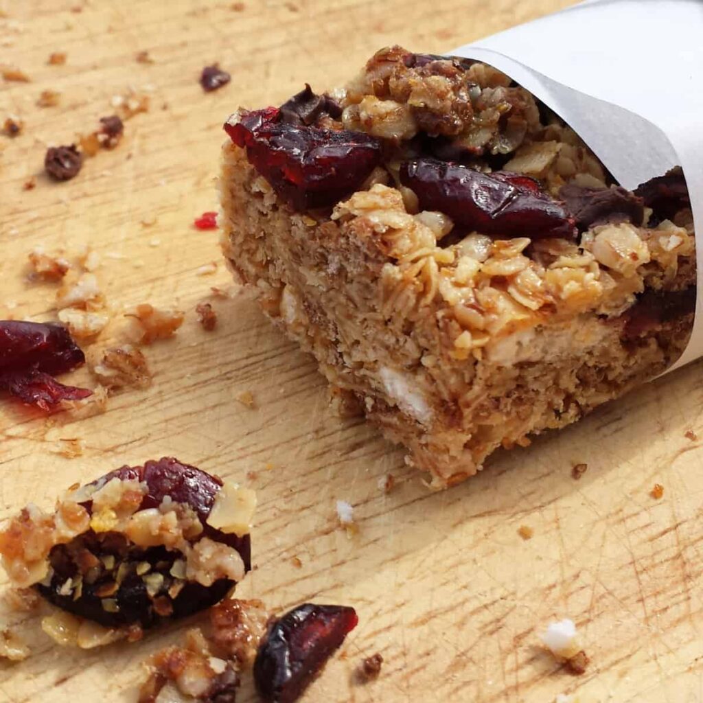 close up of a Granola Bar wrapped in parchment paper on a cutting board 