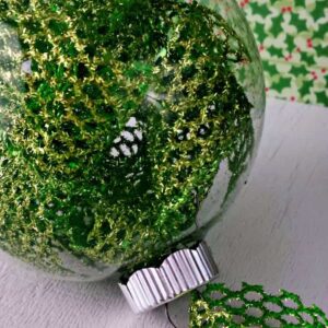 Close up image of a diy clear Christmas ornament filled with glittery ribbon..