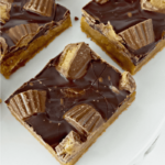 Close up image of peanut butter cup cookie bars on a white plate.
