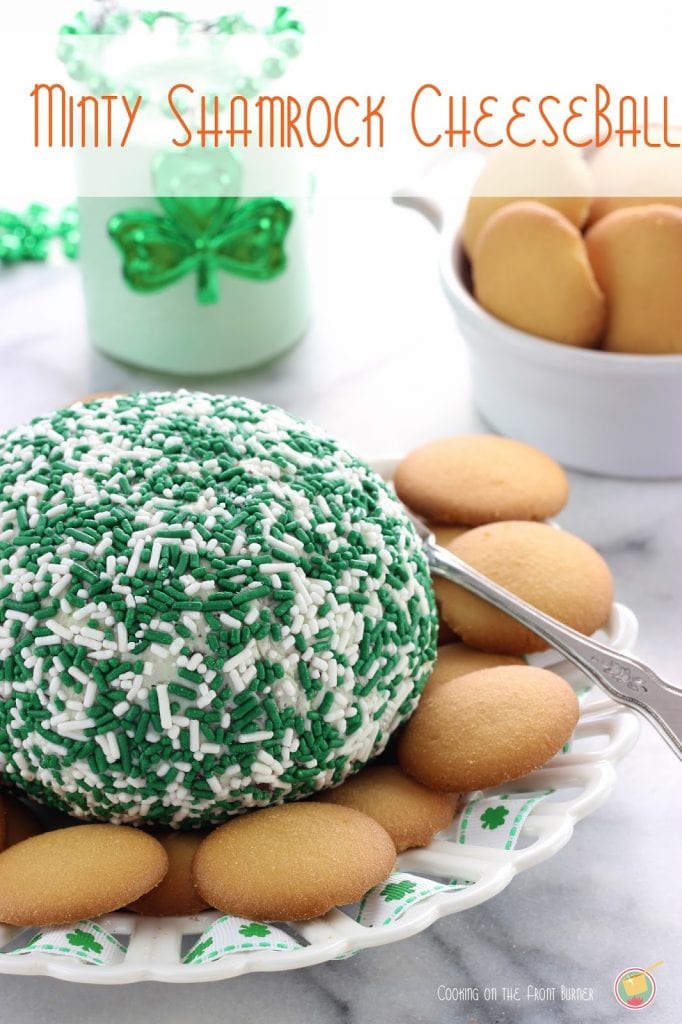 A mint cheese ball covered with green and white sprinkles surrounded by vanilla wafer cookies.