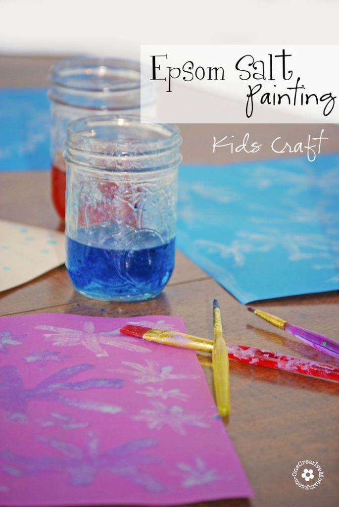 Epsom salt paint, paintbrushes and construction paper on a table top.