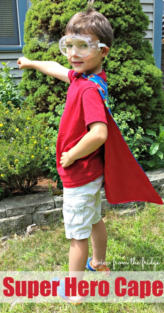 Child wearing a superhero cape and goggles.