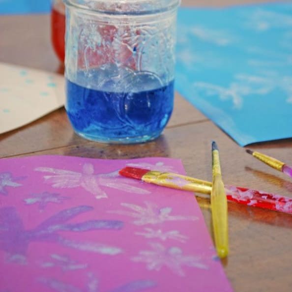 Construction paper, paint brushes, and a mason jar of colored water.