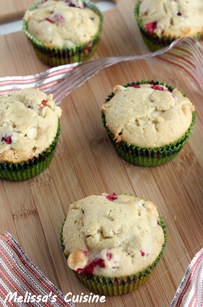 Cranberry White Chocolate Muffins on a wood surface next to festive ribbon.
