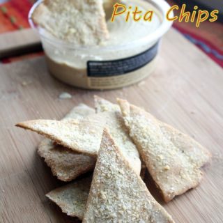 Photo of pita chips stacked high with a few in the back being dipped into hummus