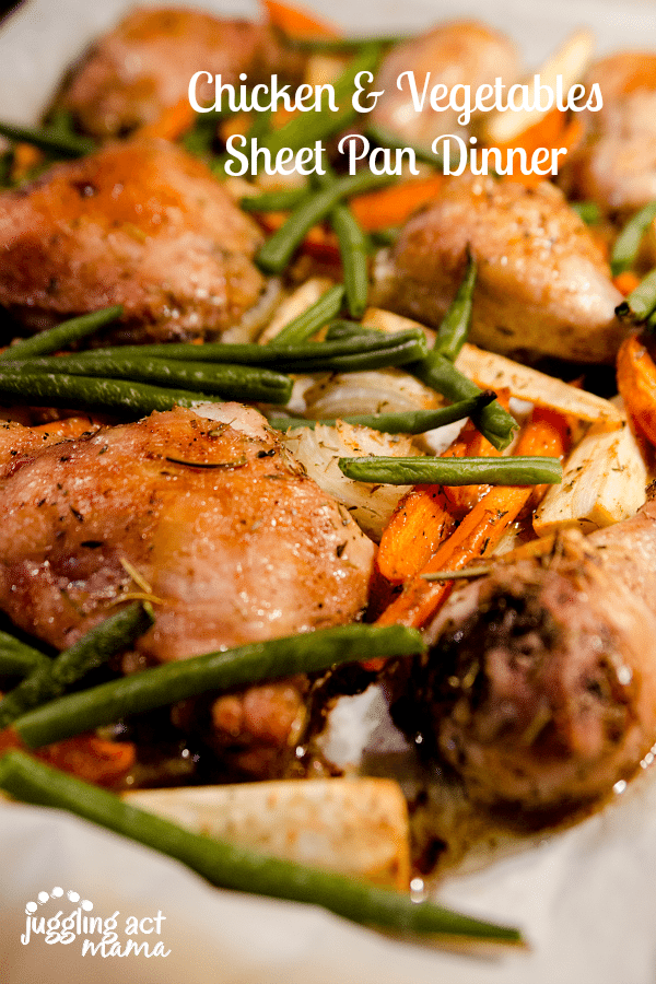 Close up image of chicken and vegetables on a parchment lined sheet pan.