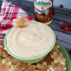 Close up image of egg nog dip with cinnamon sugar pie crust dippers on a plate along side a bottle of eggnog.