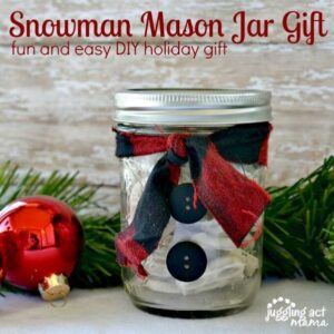 Snowman Mason Jar Gift surrounded by christmas greenery.