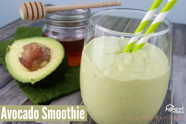 honey, halved avocado in the background with a creamy avocado and banana smoothie in front.