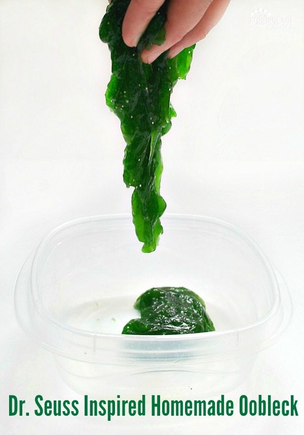 a hand holding oobleck as it oozes down into a container