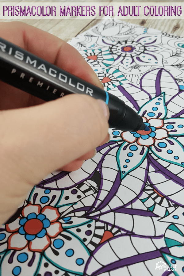 Hand holding a marker over an adult coloring page.