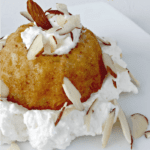 Close up image of a mini almond bundt cake topped with slivered almonds.