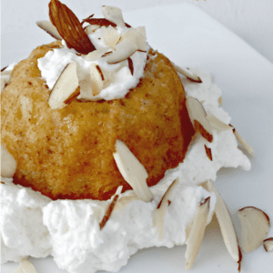 Close up image of a mini almond bundt cake topped with slivered almonds.