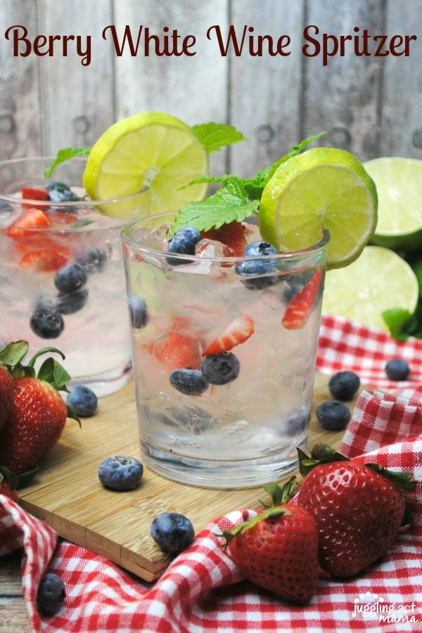 Close up of a Berry White Wine Spritzer garnished with fresh fruit and mint.