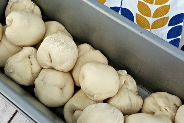 A 9x5 loaf pan is filled with dough pockets containing cream cheese and strawberry jam for showing a step in how to make Strawberry Cream Cheese Pull Apart Bread.