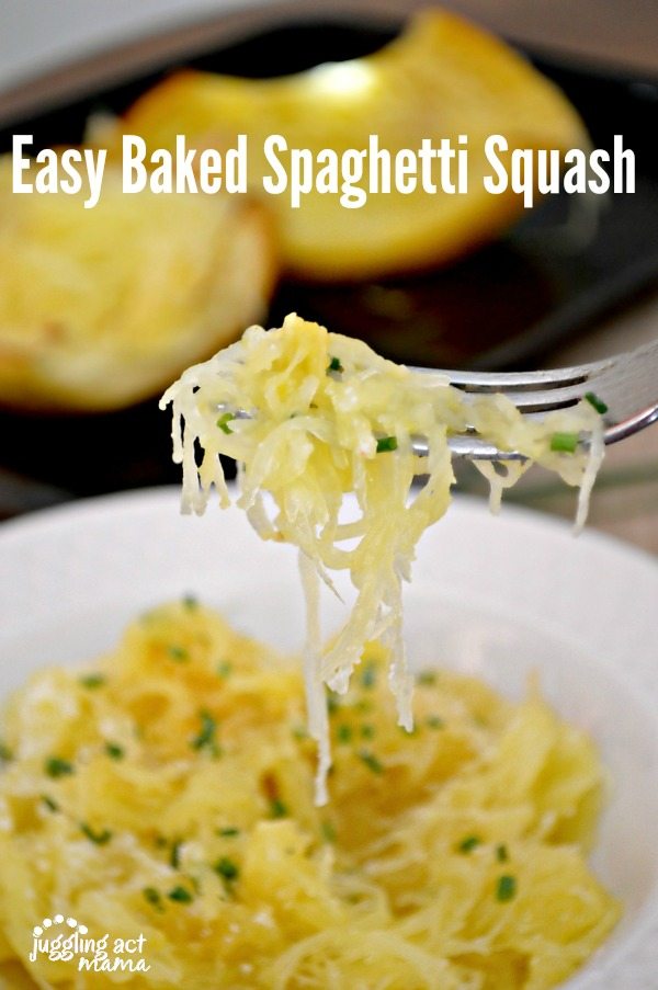 A forkful of baked spaghetti squash recipe garnished with Parmesan cheese and chives. In the back ground is a white pasta bowl full of spaghetti squash and a sheet pan with baked spaghetti squash halves.