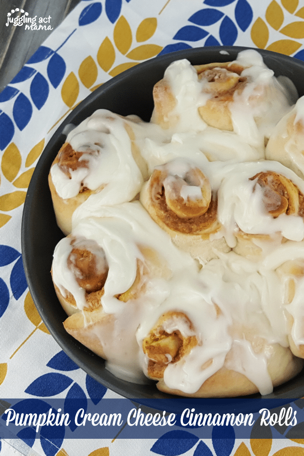 Top down image of Pumpkin Cinnamon Rolls in a baking dish on a blue and yellow towel.