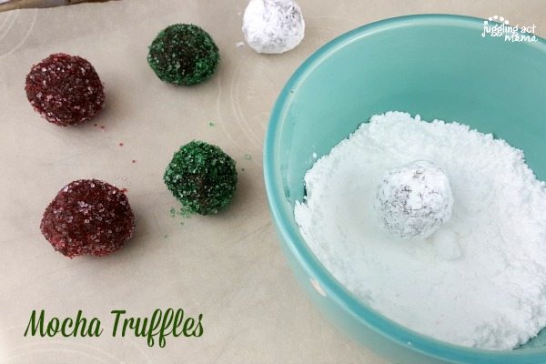 Truffles being rolled in a powdered sugar coating.