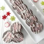 Close up, top down image of chocolate peppermint cookies on a white platter, surrounded by peppermint candies.
