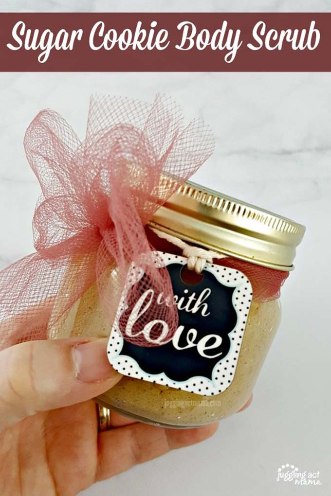 Hand holding coconut oil sugar scrub in a glass jar.