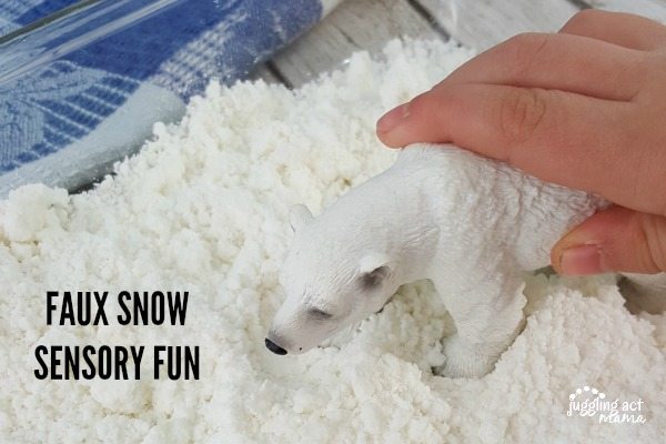 Close up image of a child's hand playing in faux snow sensory fun for snow days.