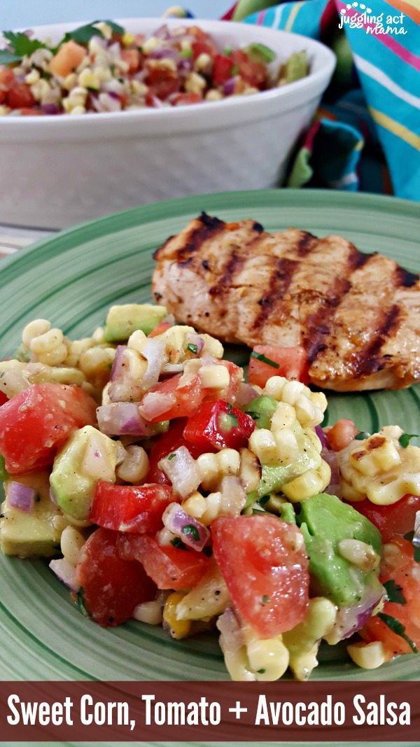 Close up of Sweet Corn, Tomato and Avocado Salsa on a green plate with grilled chicken.