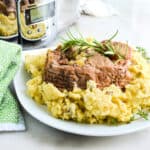 Slow cooker roast pork with apples on a bed of mashed potatoes.