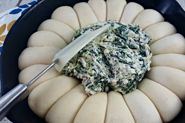 Filling the ring of garlic rolls with spinach dip.