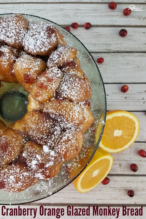 Top down image of a Christmas Monkey Bread on a cake plate, next to oranges and cranberries.