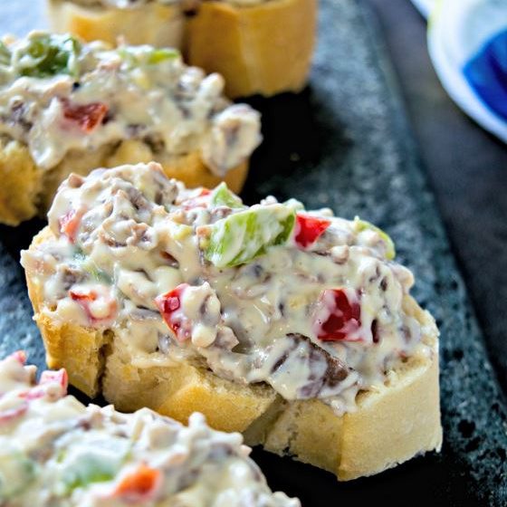 Dips for game day: Close up of Philly cheesesteak dip on sliced bread.