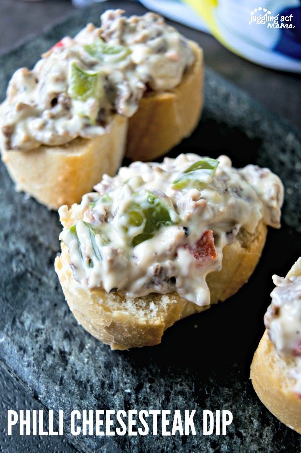 Philly Cheesesteak Dip on crostini pictured on a dark countertop.