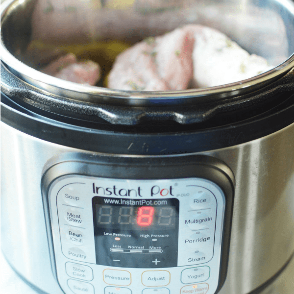 A close up of an Instant Pot reading 8 minutes with pork tenderloin inside.