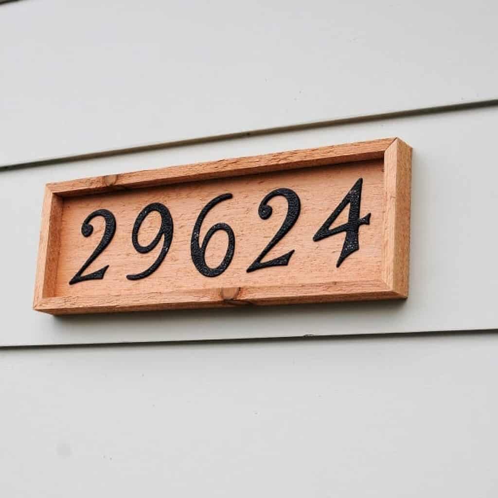 DIY wooden address plaque hanging on a house.