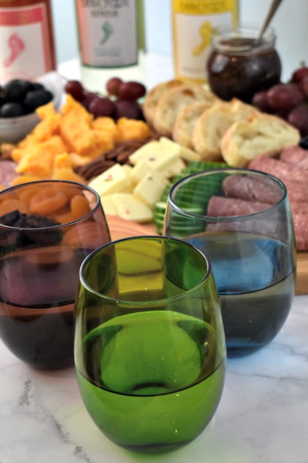 colorful wine glasses in front of a Meat and Cheese Board