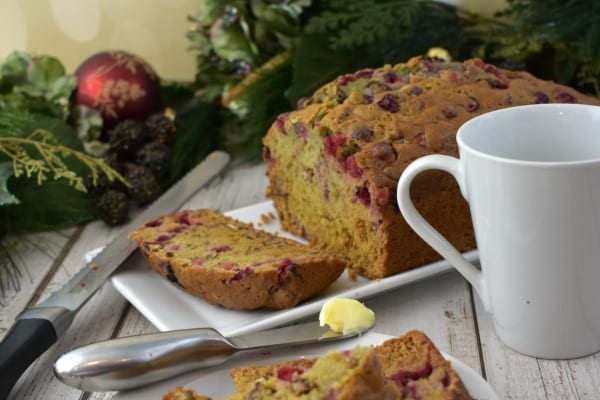 Cranberry Orange Bread next to a mug and butter knife.