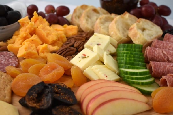 close up a platter with fruit and dried fruit, cheeses, olives, salami and more.