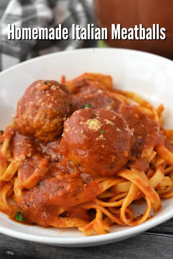 Close up of pasta with tomato sauce and meatballs in a white bowl.