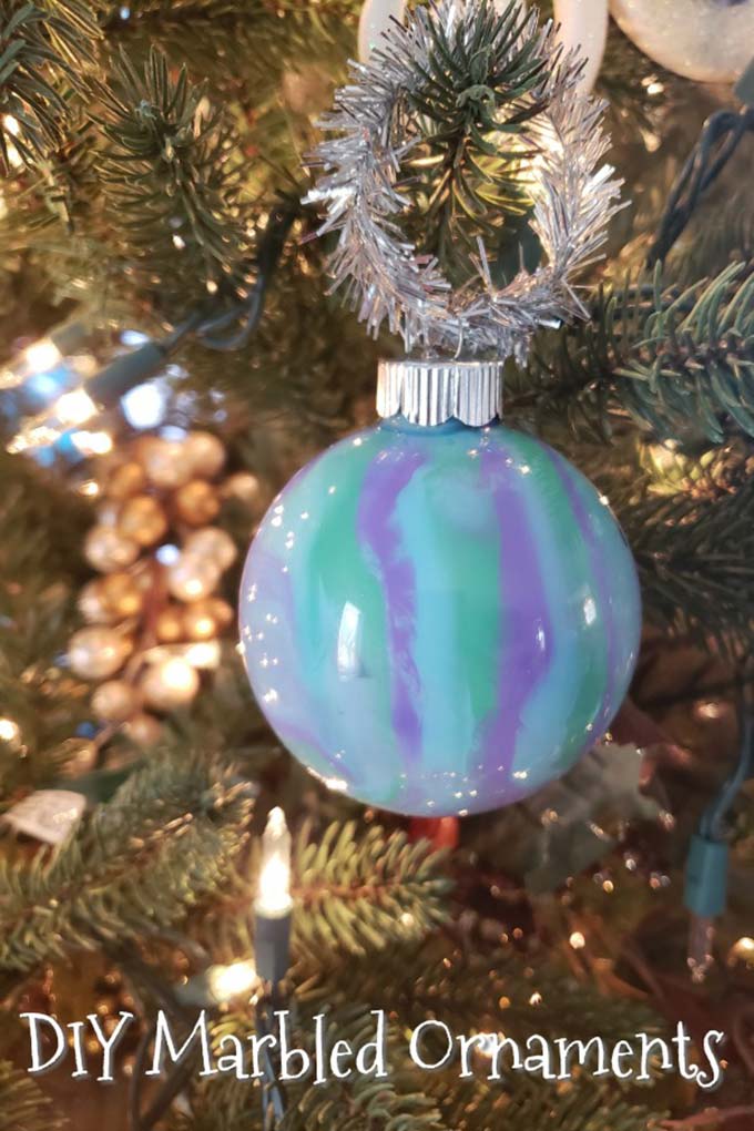 Close up image of a blue, purple, and green marble Christmas ornament on a Christmas tree. 