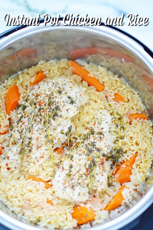 The inside of an Instant Pot with chicken, brown rice and carrots seasoned with herbs and spices.