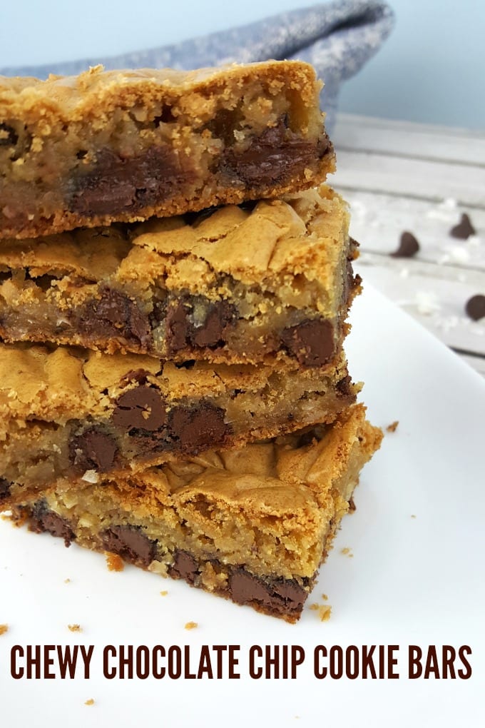 Chocolate Chip Cookie Bars stacked up on a white plate with a blue napkin in the background.