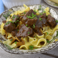 Close up image of beef tips with gravy over noodles.