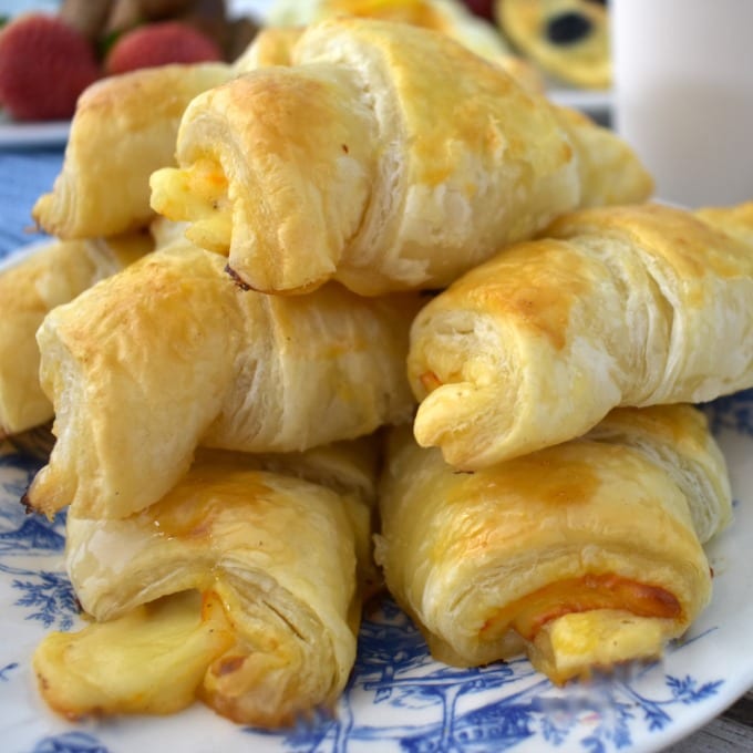 Ham and Cheese Croissants piled on a blue and white plate.