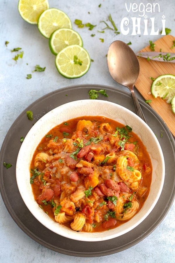 Overhead view of Vegan chili in a bowl with lemon slices and a spoon next to it