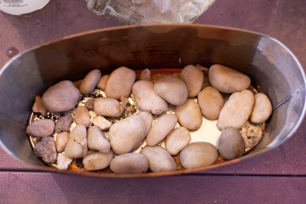Small metal planter with river rocks lining the bottom