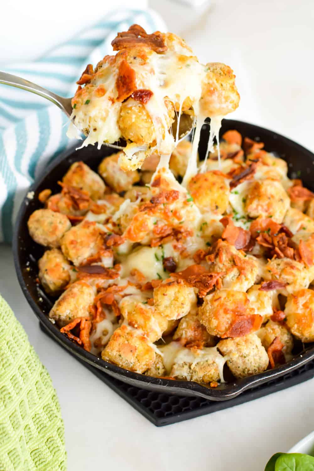 Spoonful of cheesy ranch tater tots with bacon.