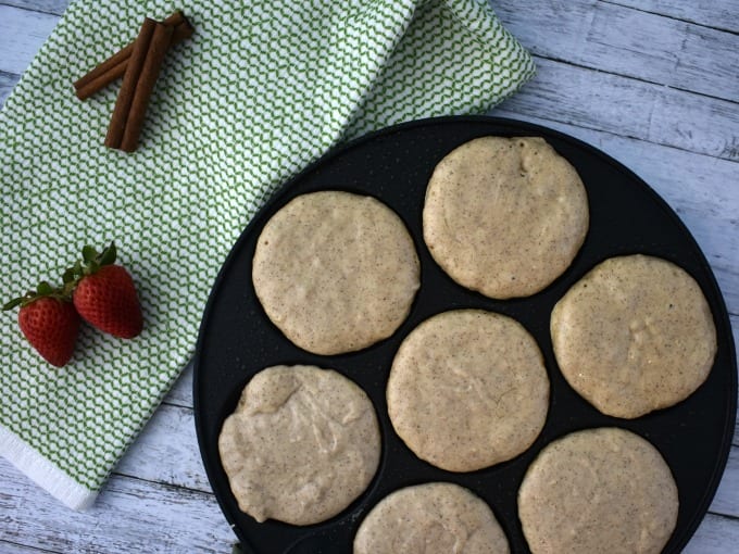 Silver Dollar Pancake Pan with Silver Dollar Pancake batter on a wooden table with a green and white cloth and fresh strawberries