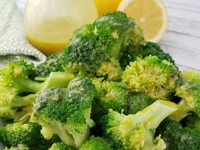Steamed Broccoli drizzled with Lemon Vinaigrette, cruet and halved lemon in the background