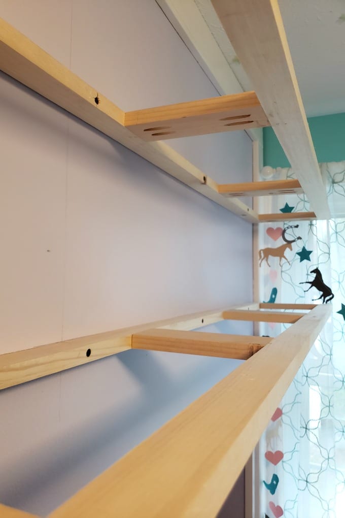 A light purple wall with the supports for pine floating shelves in place